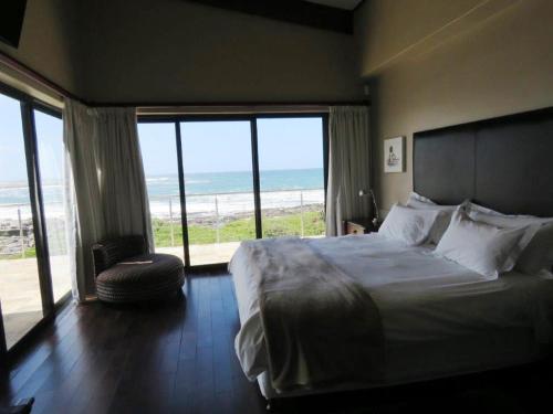 a bedroom with a bed with a view of the ocean at Whalesong Villa in Hermanus