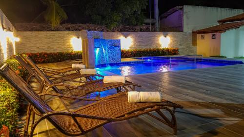 a patio with chairs and a swimming pool at night at Bem Bahia Hotel - Rede Bem Bahia in Porto Seguro