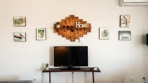 a flat screen tv on a white wall with pictures at Kerkini Houses in Kerkíni