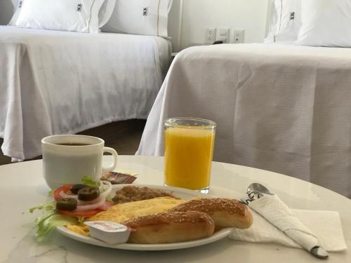 um prato de comida para o pequeno-almoço e um copo de sumo de laranja em Six Hotel Guadalajara Degollado em Guadalajara