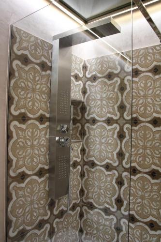 a bathroom with a shower with a tile wall at La Dimora del Principe-Piano terra in Trani