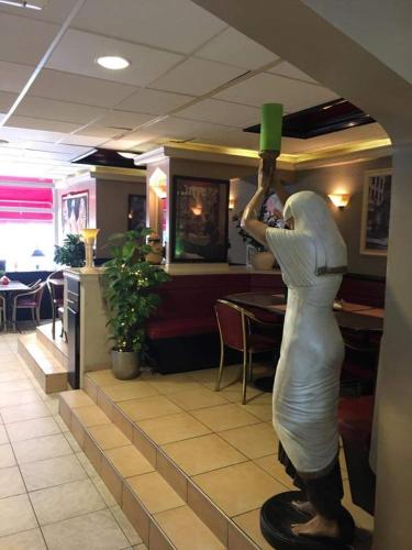 a statue of a woman holding a green cup in a restaurant at Tamar 2 in Katwijk aan Zee