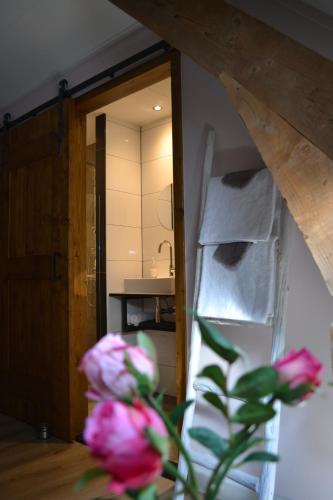 a vase with pink flowers in front of a mirror at Bed & Breakfast aan de Beek in Arcen