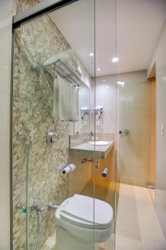 a bathroom with a toilet and a glass shower at Novares Hotel in Goiânia