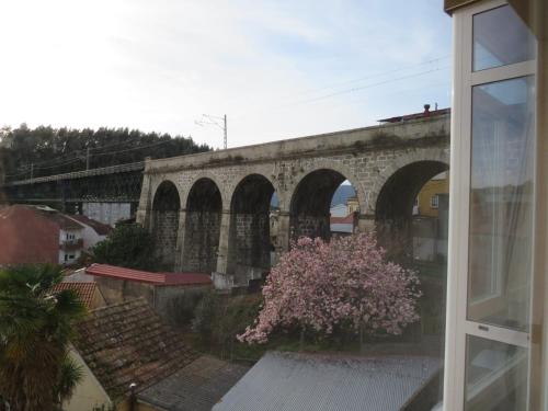 a view of a stone bridge with a flowering tree at CAMIÑO DA PRATA in Redondela