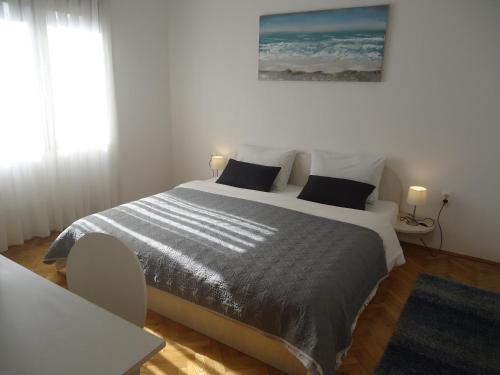 a white bedroom with a large bed with black pillows at Apartment Kate in Trogir