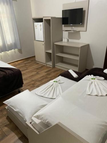 a hotel room with two beds and a tv at Hotel Panorâmico in Penha