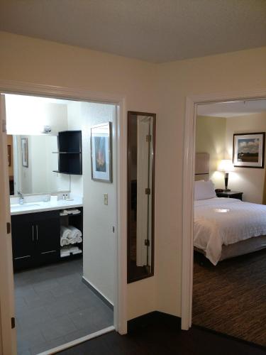 a bedroom with a bed and a bathroom with a sink at Candlewood Suites Olive Branch by IHG in Olive Branch