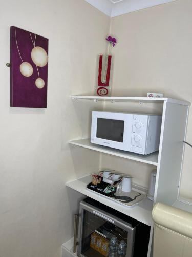 a small kitchen with a microwave on a shelf at The Railway Sleeper Lodge in Colchester