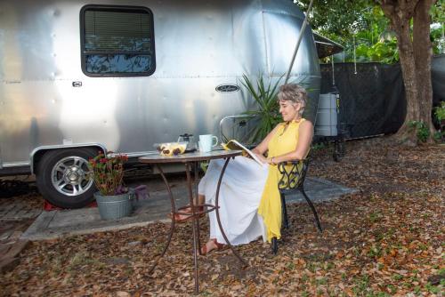 a woman sitting at a table in front of a trailer at Airstream in the Center of it All in Miami