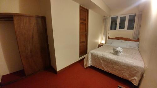 a bedroom with a bed with a teddy bear on it at Hostal El Peregrino in Cusco