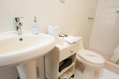 a white bathroom with a sink and a toilet at Hostal El Peregrino in Cusco