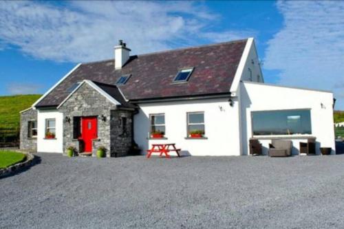 a white house with a red door and a picnic table at Cliffs View Self Catering @ Limestone Lodge in Doolin