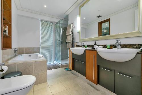 La salle de bains est pourvue de 2 lavabos, d'une baignoire et de toilettes. dans l'établissement Ultimate outdoor-living Urban Getaway! 1 Carpark, à Auckland