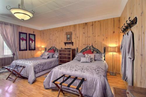 two beds in a room with wood paneled walls at Les Gites Makadan in Normandin