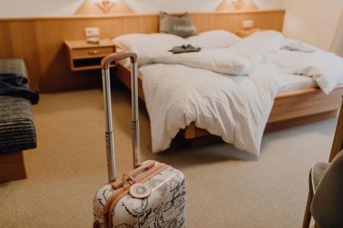 a hotel room with a bed with a suitcase at Dorfcafe Unken Hotelpension sWirtshaus im Dorf in Unken