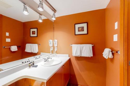 a bathroom with a white sink and an orange wall at Glacier's Reach 115 in Whistler