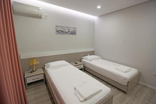 two beds in a small room with a window at Hotel Star in Sarandë