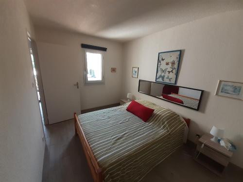 une chambre avec un lit avec un oreiller rouge dessus dans l'établissement Hélios 32, T2 climatisé, parking, 500m plage, au Cap d'Agde