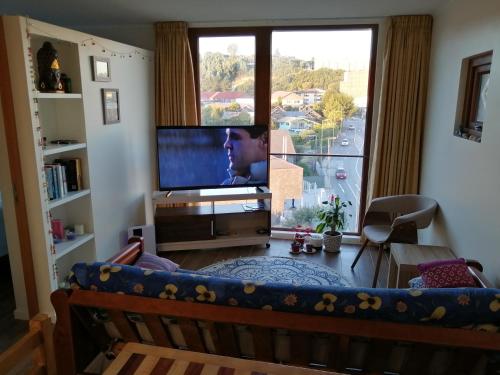 a person sitting on a couch in front of a television at Departamento 1D 1B, Puerto Montt in Puerto Montt