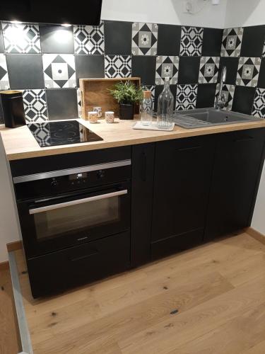 a kitchen with a counter with a sink and a stove at LOUHANS Les Petites Arcades avec ses deux appartements coté Arcades et coté cour in Louhans