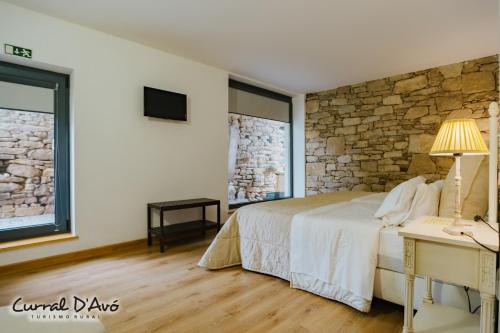 a bedroom with a bed and a stone wall at Curral D Avó Turismo Rural & SPA in Caçarelhos