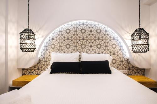 a bedroom with a white bed with two black pillows at Amer Villa Santorini with outdoor hot tub in Vóthon