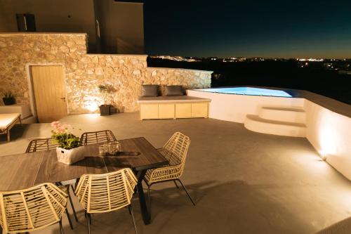 un patio con mesa, sillas y piscina en Amer Villa Santorini with outdoor hot tub en Vóthon