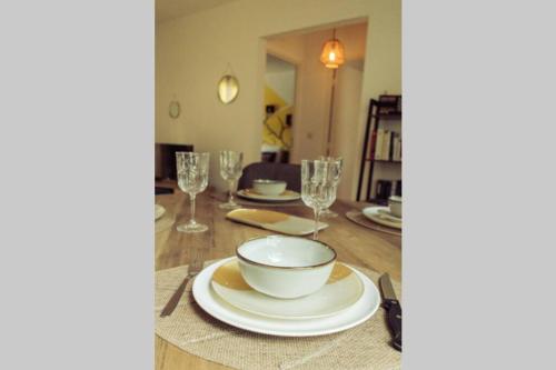 a table with a bowl and plates and glasses at L'île au paon - Appartement T2 avec piscine et parking in Les Abymes