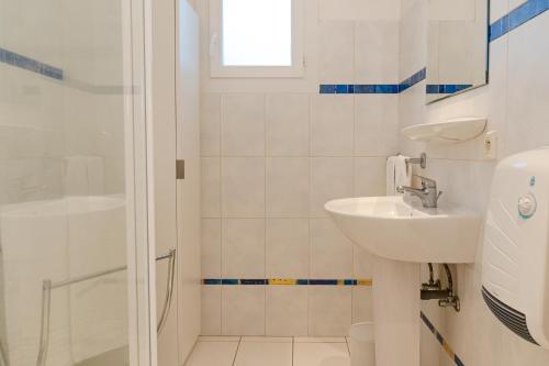 a white bathroom with a sink and a shower at Résidence Marie Diane - Laurier des Montagnes in Propriano