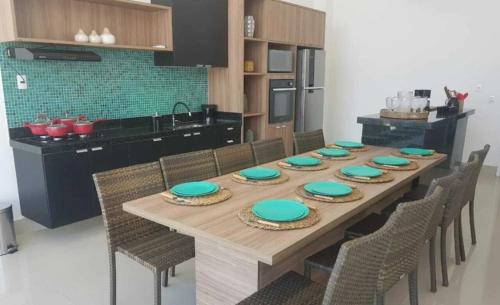 ein langer Holztisch mit Stühlen und eine Küche in der Unterkunft Muro Alto Condomínio Clube - Porto de Galinhas in Porto De Galinhas