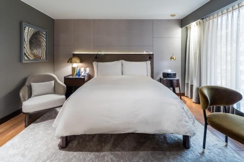 a bedroom with a large white bed and two chairs at Sofitel Bogota Victoria Regia in Bogotá