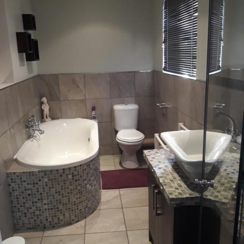 a bathroom with a tub and a toilet and a sink at Fancy Pansy in Germiston