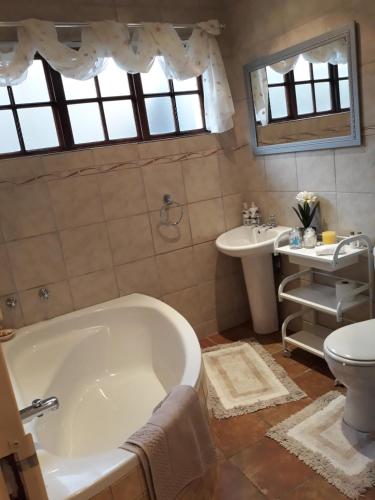 a bathroom with a tub and a toilet and a sink at Fancy Pansy in Germiston