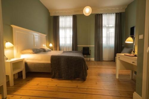 Hotel Saxkjøbing في Sakskøbing: غرفة نوم بسرير كبير ونوافذ
