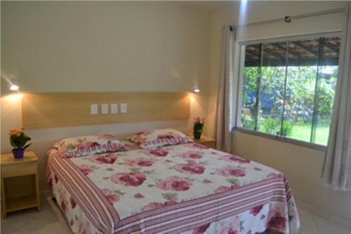 a bedroom with a bed with a large window at Pousada e Restaurante Kambuká in Mucuri