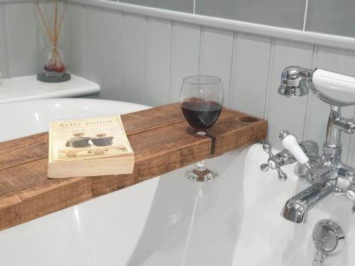 a glass of wine on a wooden shelf in a bath tub at The Flying Scotsman Flamborough in Flamborough
