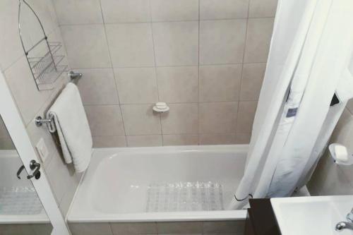 La salle de bains est pourvue d'une baignoire blanche et d'une douche. dans l'établissement FIN DEL MUNDO - EDIFICIO AUSTRALIS, à Ushuaia