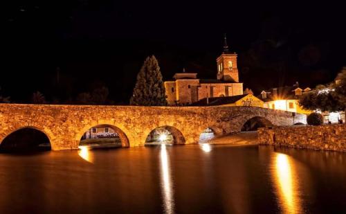 a stone bridge over a river at night at Hotel Molina Real in Molinaseca
