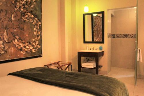 a bedroom with a bed and a bathroom with a sink at Hotel del Angel in Guadalajara