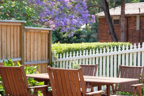 een houten tafel en stoelen voor een hek bij Garden Apartment - Short Walk to Harbour Bridge in Sydney