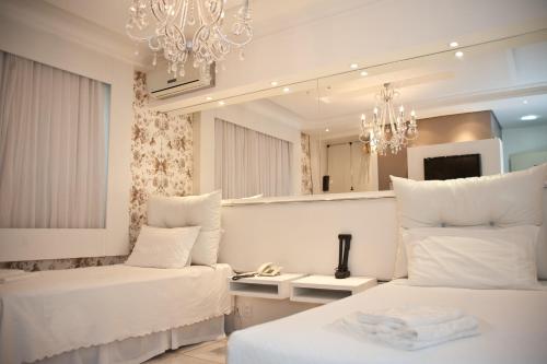 a hotel room with two beds and a chandelier at Germanias Blumen Hotel in Passo Fundo