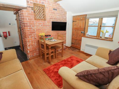 sala de estar con mesa y pared de ladrillo en Top Farm Cottage, en Oswestry