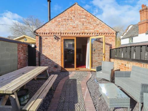 a patio with a wooden bench and a table at Top Farm Lodge in Oswestry