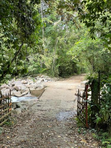 a dirt road with a fence next to a creek at Finca Isla Rainforest Retreat in Aguas Zarcas