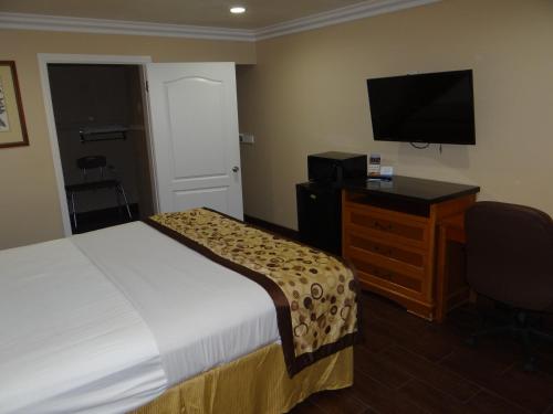 a hotel room with a bed and a desk and a television at Rodeway Inn in Cypress