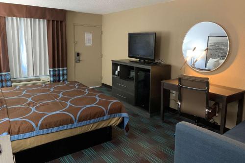 Habitación de hotel con cama, TV y espejo. en Super 8 by Wyndham Newport News, en Newport News