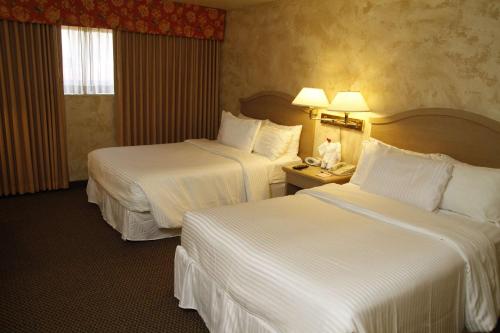 a hotel room with two beds with white sheets at Ramada by Wyndham Viscount Suites Tucson East in Tucson