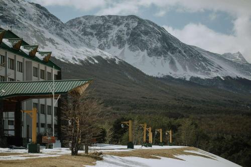 a building with a snow covered mountain in the background at Wyndham Garden Ushuaia Hotel del Glaciar in Ushuaia