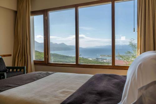 a bedroom with a large window with a view of the ocean at Wyndham Garden Ushuaia Hotel del Glaciar in Ushuaia